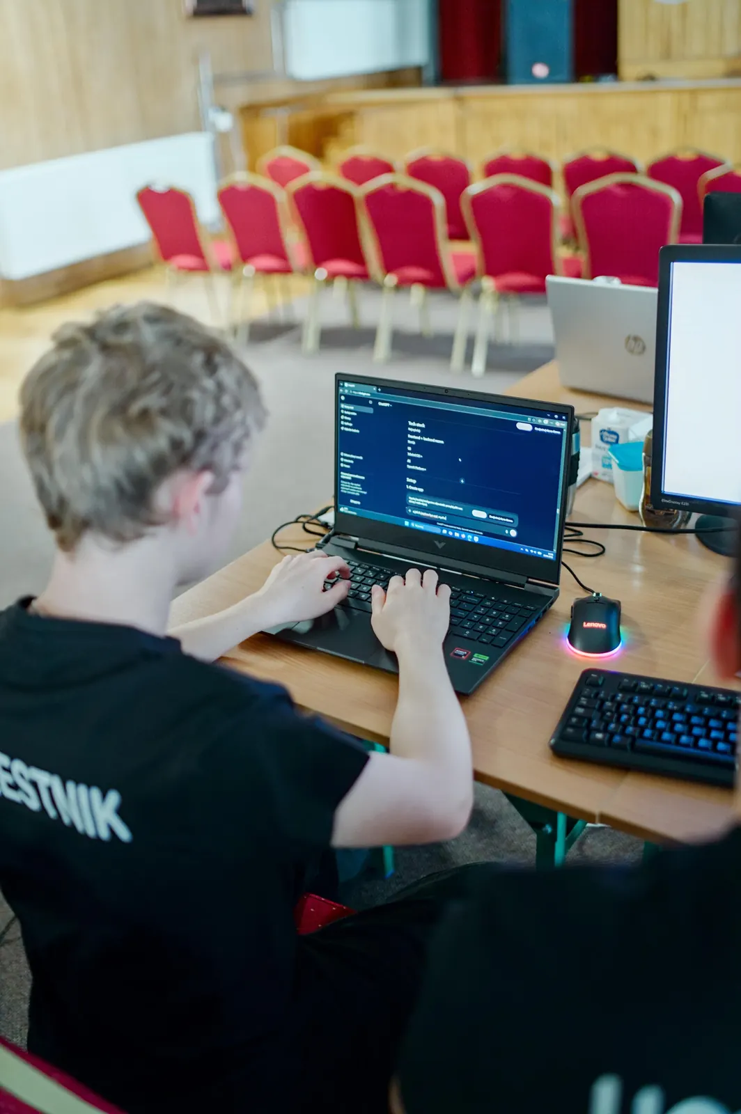Uczestnik rozpisuje stack technologiczny z pomocą AI na laptopie